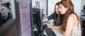 Zwei junge Frauen schauen sich gemeinsam etwas auf Computerbildschirm an